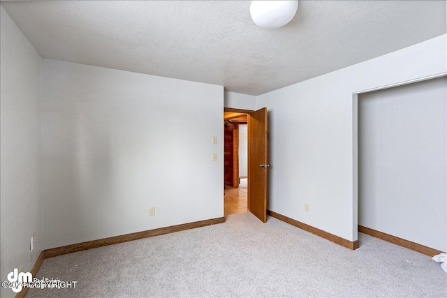 unfurnished bedroom with light colored carpet and a textured ceiling