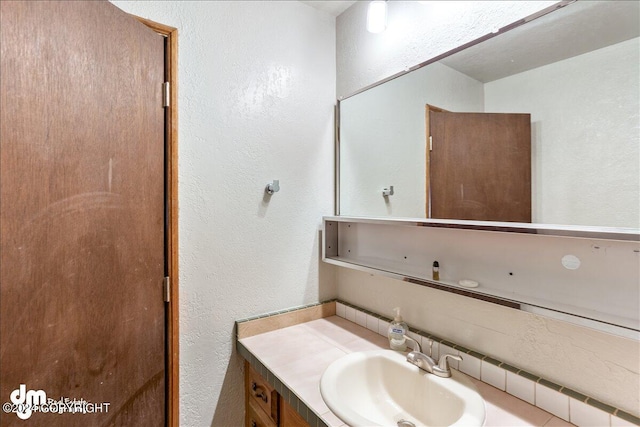 bathroom featuring a textured wall and vanity