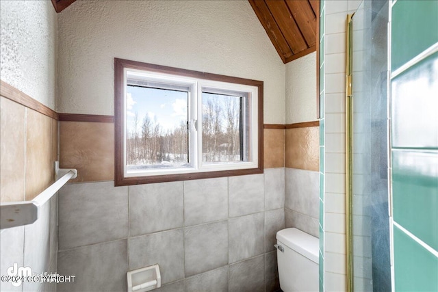 bathroom featuring vaulted ceiling, tile walls, and toilet