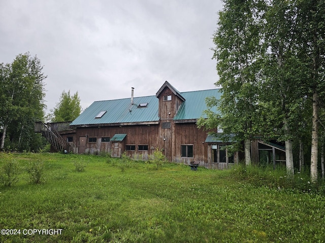 back of house featuring a yard and metal roof