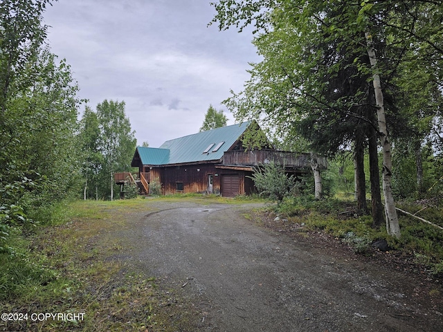 view of front of house with a garage, metal roof, driveway, and a deck