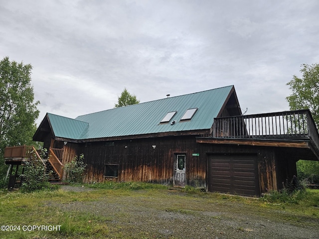 view of front facade featuring dirt driveway, metal roof, and a garage