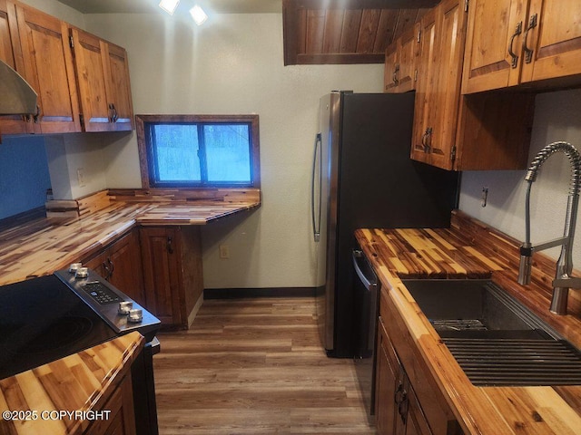 kitchen with wood-type flooring, sink, wood counters, and electric stove