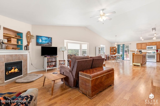 living room featuring ceiling fan, light hardwood / wood-style flooring, a fireplace, and lofted ceiling