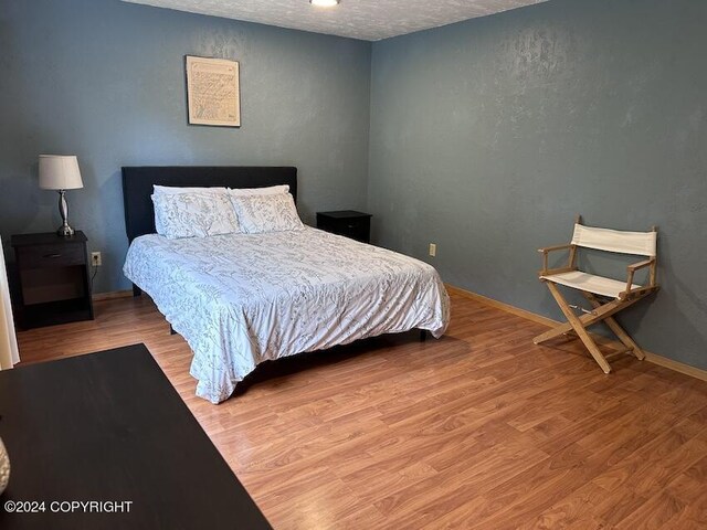 bedroom with light hardwood / wood-style flooring and a textured ceiling