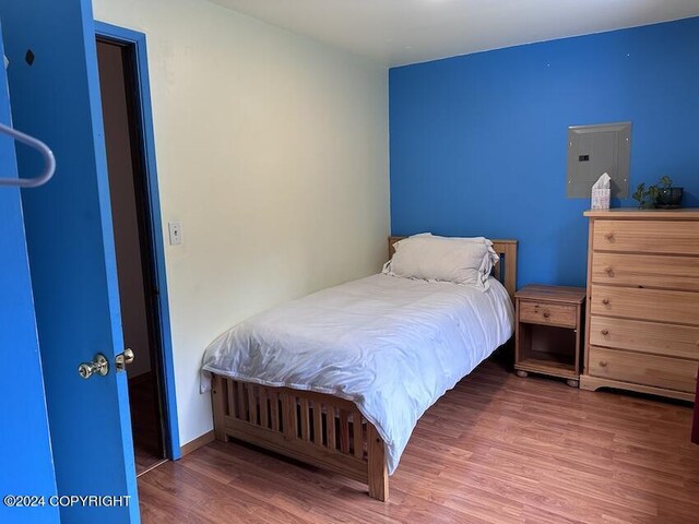 bedroom with electric panel and hardwood / wood-style flooring