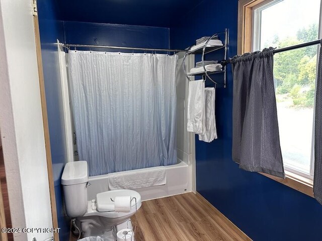 bathroom featuring shower / tub combo with curtain, toilet, and hardwood / wood-style flooring