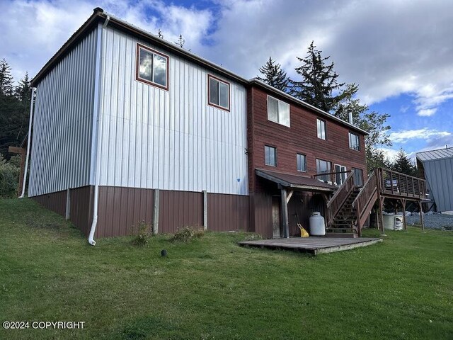 rear view of property featuring a wooden deck and a lawn