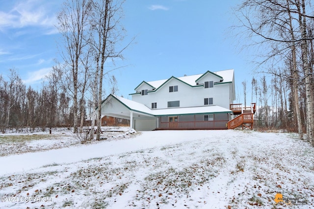 snow covered rear of property featuring a carport and a deck