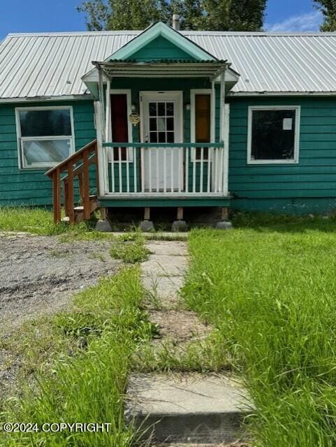 rear view of house featuring covered porch and a lawn