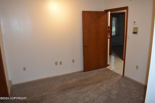 carpeted spare room featuring baseboard heating