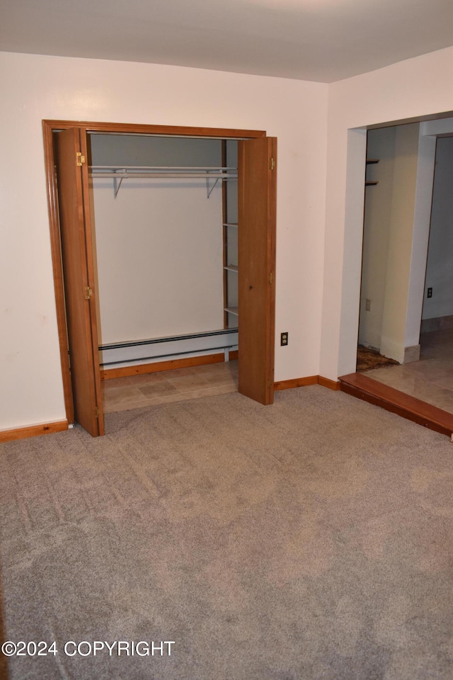 unfurnished bedroom with carpet floors and a baseboard radiator