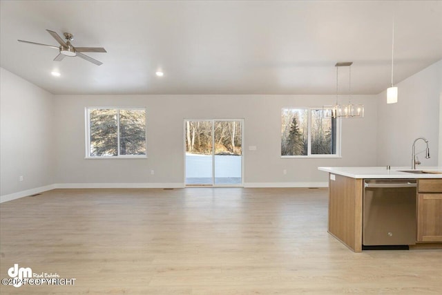 kitchen with sink, ceiling fan with notable chandelier, decorative light fixtures, stainless steel dishwasher, and light wood-type flooring