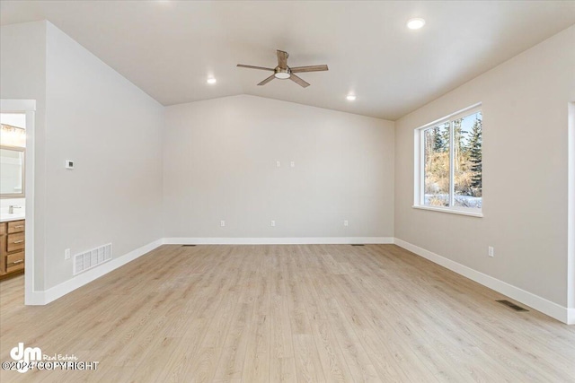 spare room with ceiling fan, light wood-type flooring, and vaulted ceiling