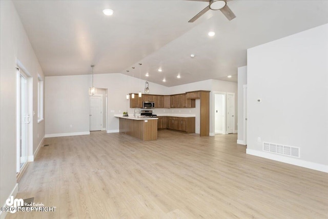 kitchen featuring a kitchen island, light wood-type flooring, appliances with stainless steel finishes, decorative light fixtures, and lofted ceiling