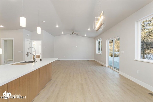 kitchen featuring vaulted ceiling, sink, ceiling fan, light hardwood / wood-style flooring, and decorative light fixtures