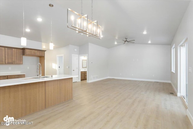 kitchen featuring light hardwood / wood-style flooring, high vaulted ceiling, hanging light fixtures, sink, and ceiling fan with notable chandelier