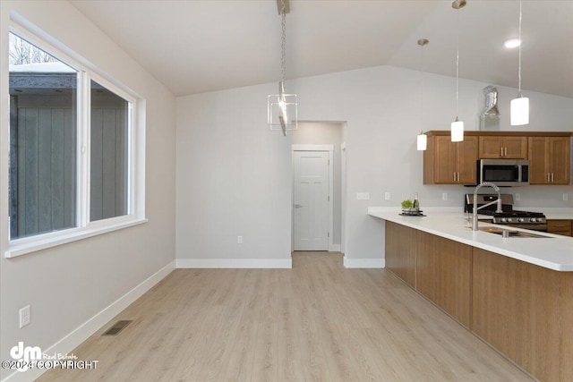 kitchen with pendant lighting, kitchen peninsula, appliances with stainless steel finishes, and light wood-type flooring