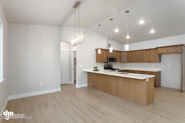 kitchen with appliances with stainless steel finishes, decorative light fixtures, sink, light hardwood / wood-style floors, and kitchen peninsula