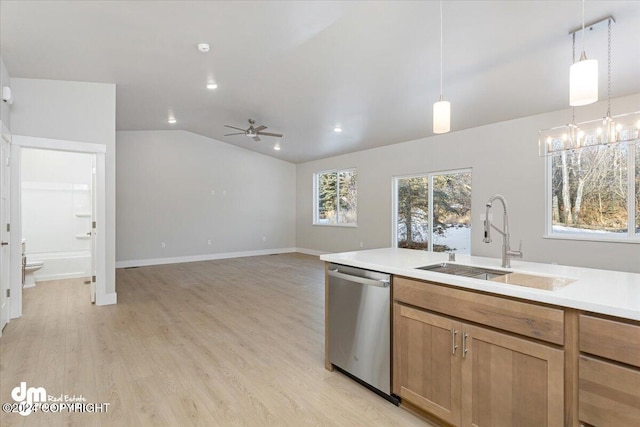 kitchen featuring vaulted ceiling, hanging light fixtures, sink, stainless steel dishwasher, and light wood-type flooring