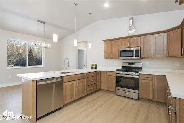 kitchen with stainless steel appliances, vaulted ceiling, kitchen peninsula, hanging light fixtures, and light hardwood / wood-style flooring