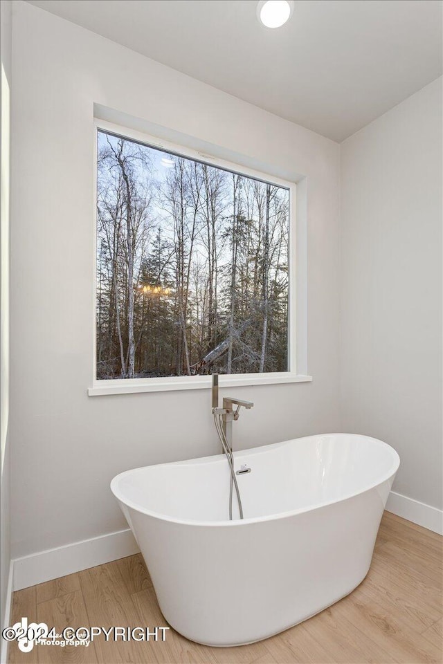 bathroom with hardwood / wood-style floors, a wealth of natural light, and a washtub