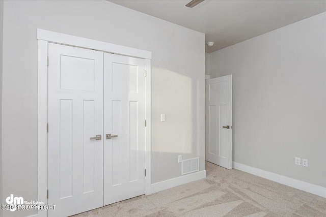 unfurnished bedroom with light colored carpet, ceiling fan, and a closet