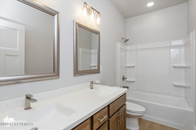 full bathroom featuring hardwood / wood-style floors, vanity, shower / tub combination, and toilet