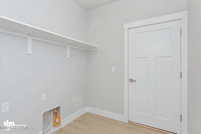 clothes washing area featuring electric dryer hookup and light hardwood / wood-style floors