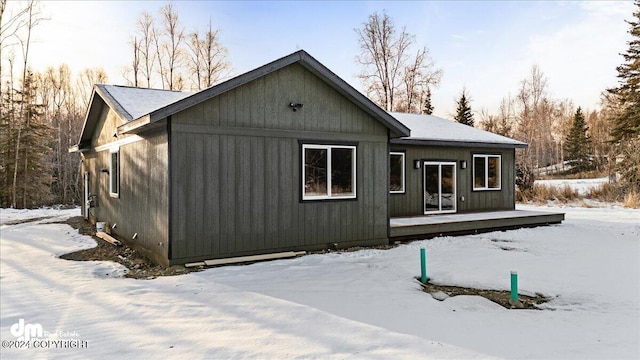 snow covered rear of property with a deck