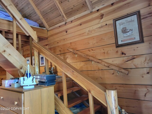 stairway featuring wood walls, wooden ceiling, and vaulted ceiling with beams