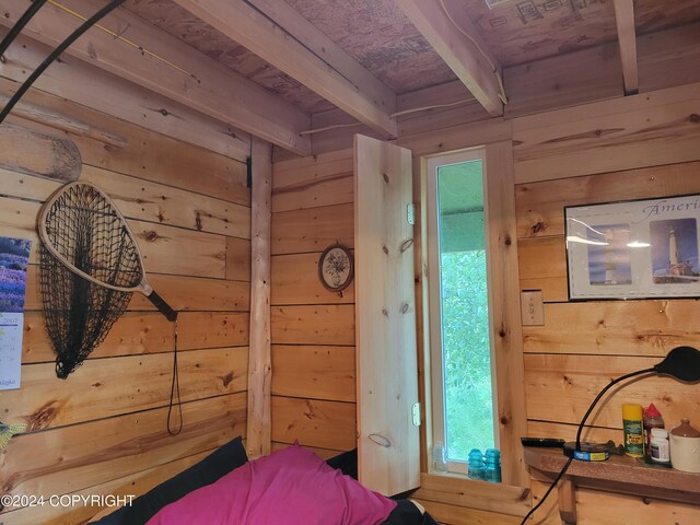 bedroom with wooden walls, beamed ceiling, and wood ceiling