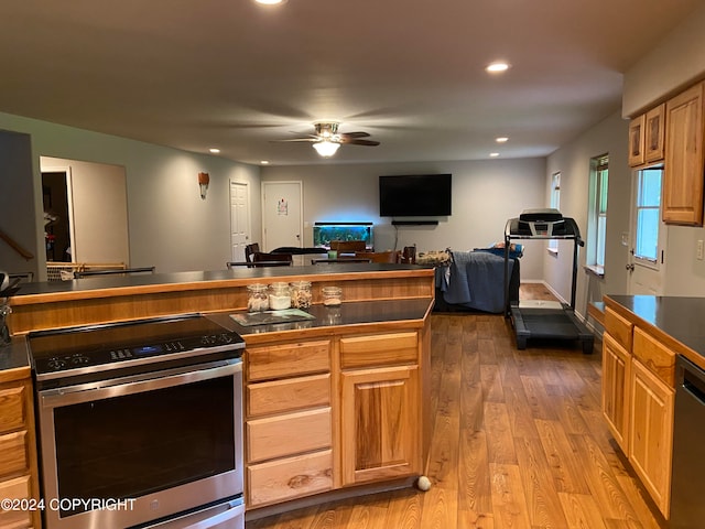 kitchen featuring ceiling fan, hardwood / wood-style flooring, black dishwasher, and stainless steel range with electric stovetop