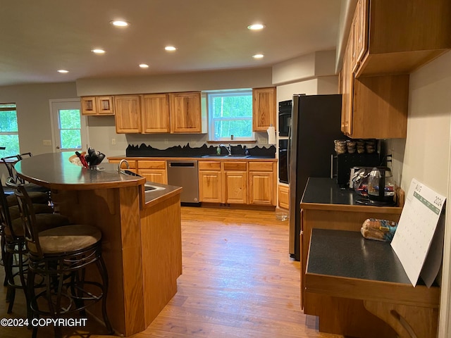 kitchen with oven, light hardwood / wood-style flooring, stainless steel dishwasher, and sink