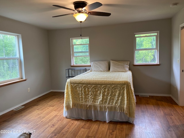 unfurnished bedroom with ceiling fan, wood-type flooring, and multiple windows