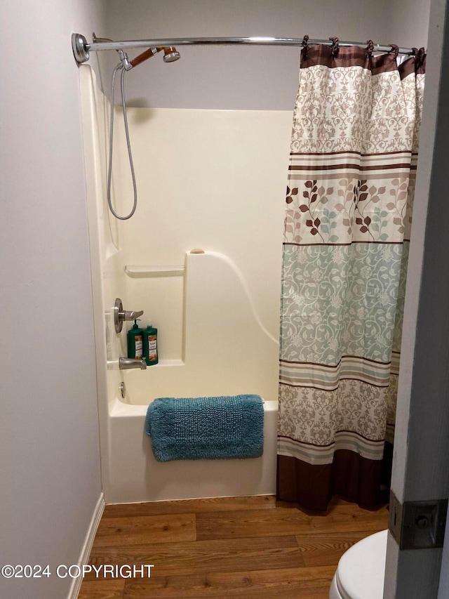 bathroom featuring hardwood / wood-style flooring, toilet, and shower / tub combo with curtain