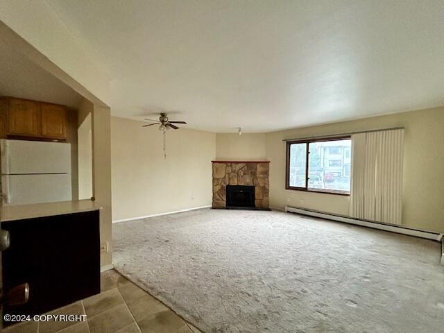 unfurnished living room with a stone fireplace, baseboard heating, light colored carpet, and ceiling fan