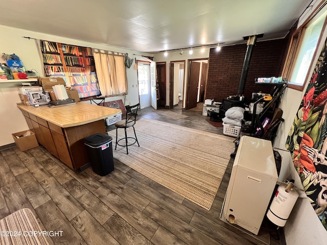 interior space with a wood stove, a breakfast bar area, track lighting, and dark hardwood / wood-style floors