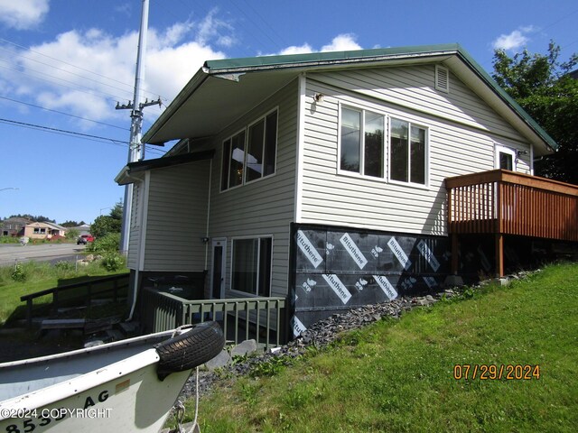 view of side of property featuring a wooden deck and a lawn