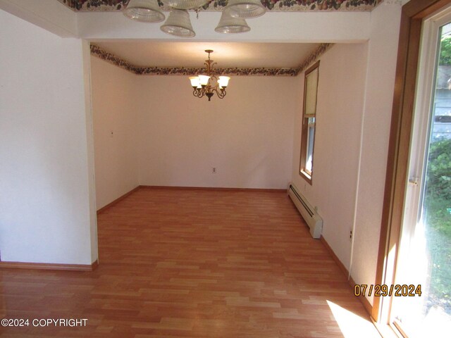 unfurnished room featuring wood-type flooring, a baseboard radiator, and a chandelier