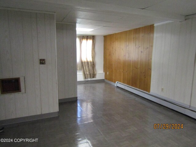 spare room featuring wood walls and a baseboard heating unit