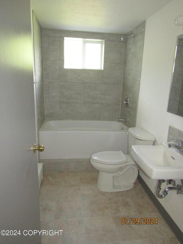 full bathroom with toilet, tiled shower / bath combo, tile patterned flooring, and sink