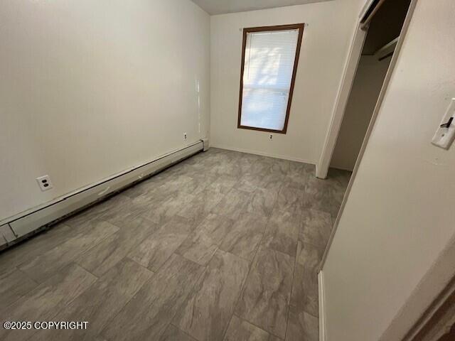 unfurnished bedroom with a baseboard heating unit