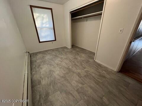 unfurnished bedroom with a closet and a baseboard radiator