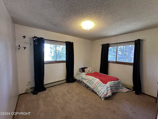 bedroom featuring a textured ceiling, baseboard heating, and light colored carpet