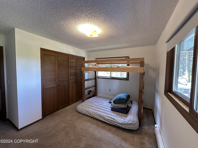 bedroom featuring a closet, a baseboard radiator, carpet, and a textured ceiling