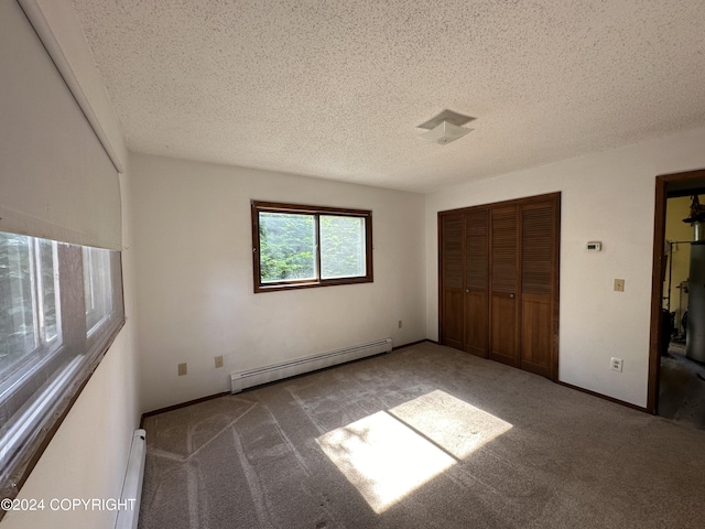 unfurnished bedroom with a closet, carpet flooring, a textured ceiling, and a baseboard heating unit