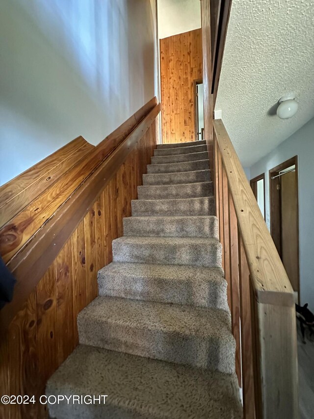 stairs featuring a textured ceiling