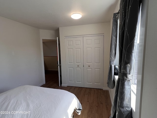 bedroom with dark wood-type flooring and a closet