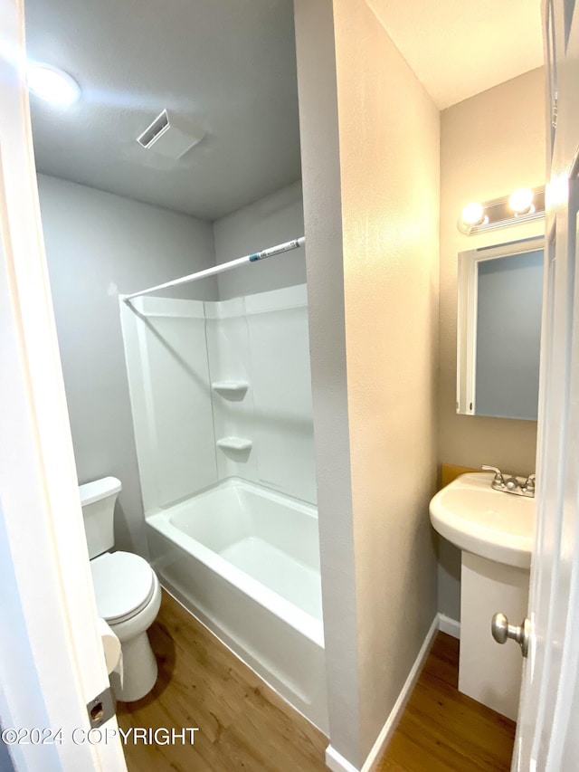 bathroom featuring wood-type flooring, toilet, and bathing tub / shower combination